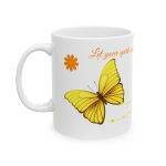 White ceramic mug with orange lettering “Let your spirit soar on wings of transformation,” decorated with yellow butterflies and orange daisy flowers.